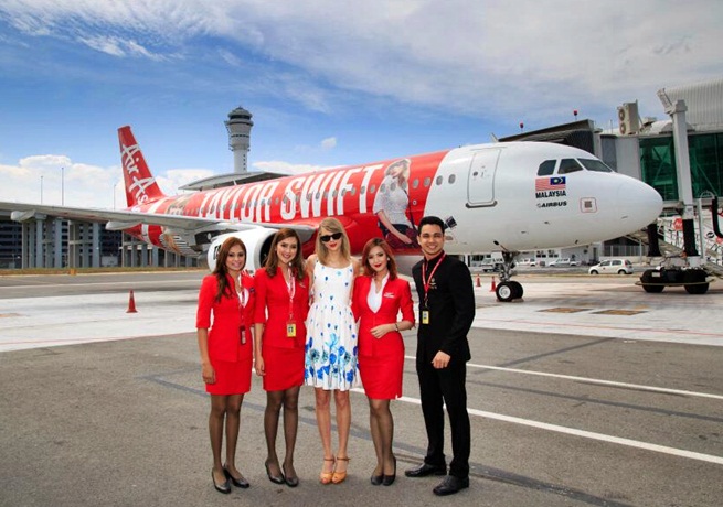 Taylor Swift posing in front of Air Asia plane red tour